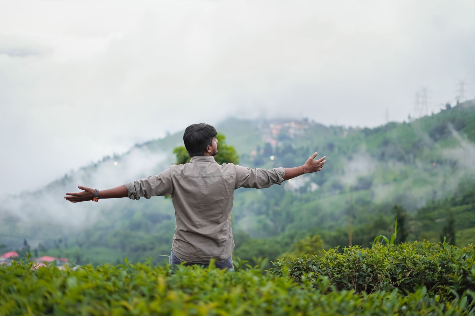 A traveler walking through misty tea plantations in Kerala during India monsoon season