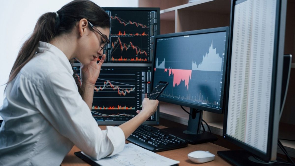 A focused Indian woman reviewing her sovereign gold bonds portfolio on a laptop at her office desk