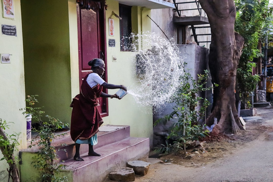 A woman using her rooftop rainwater harvesting setup during the monsoon season in an Indian home