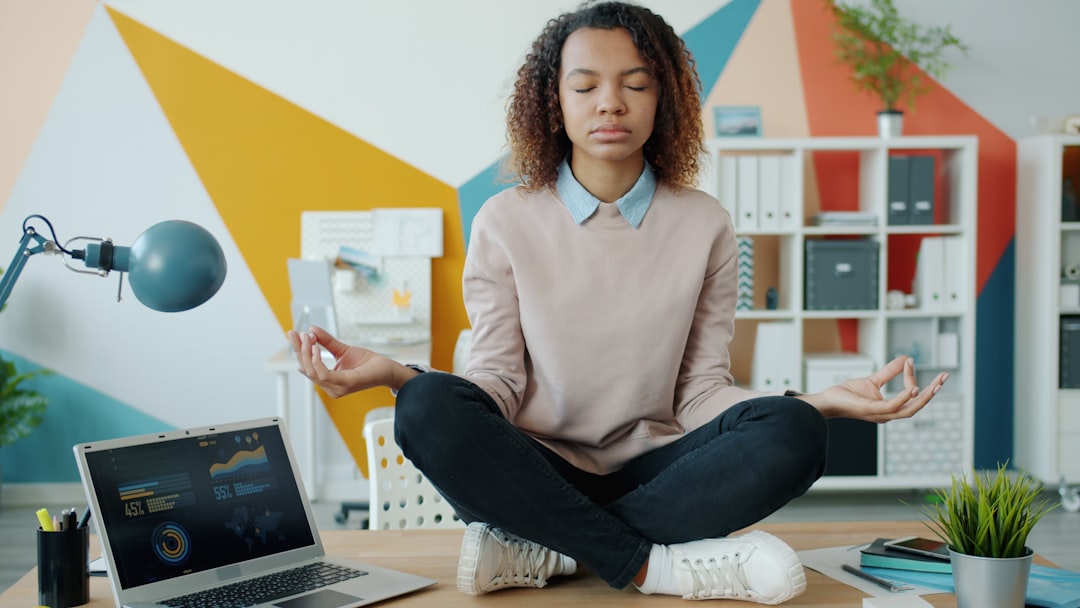 Indian woman practising pranayama breathwork at her home office desk with eyes closed