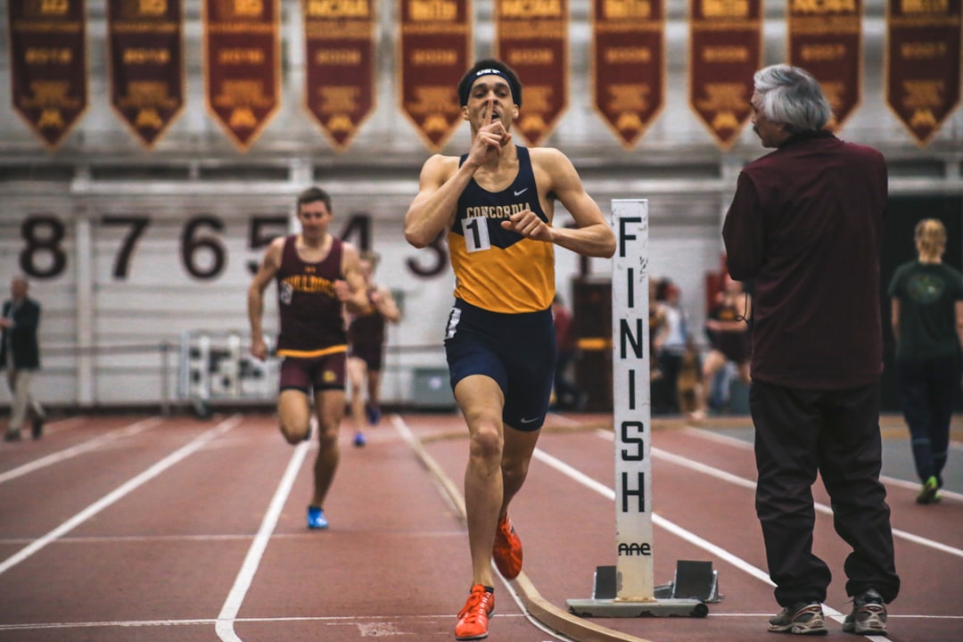 A young Indian athlete running on an indoor track during monsoon training, focused and in full stride