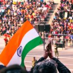 A woman in traditional dress holds the Indian tricolour at an Indian diaspora Independence Day ceremony abroad.