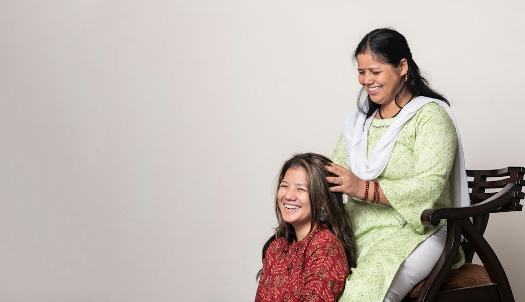 A woman performing a traditional scalp care oil massage on her long dark Indian hair at home