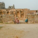 A solo female traveler stands inside the stone gateway of one of the lesser-known Deccan forts in Karnataka