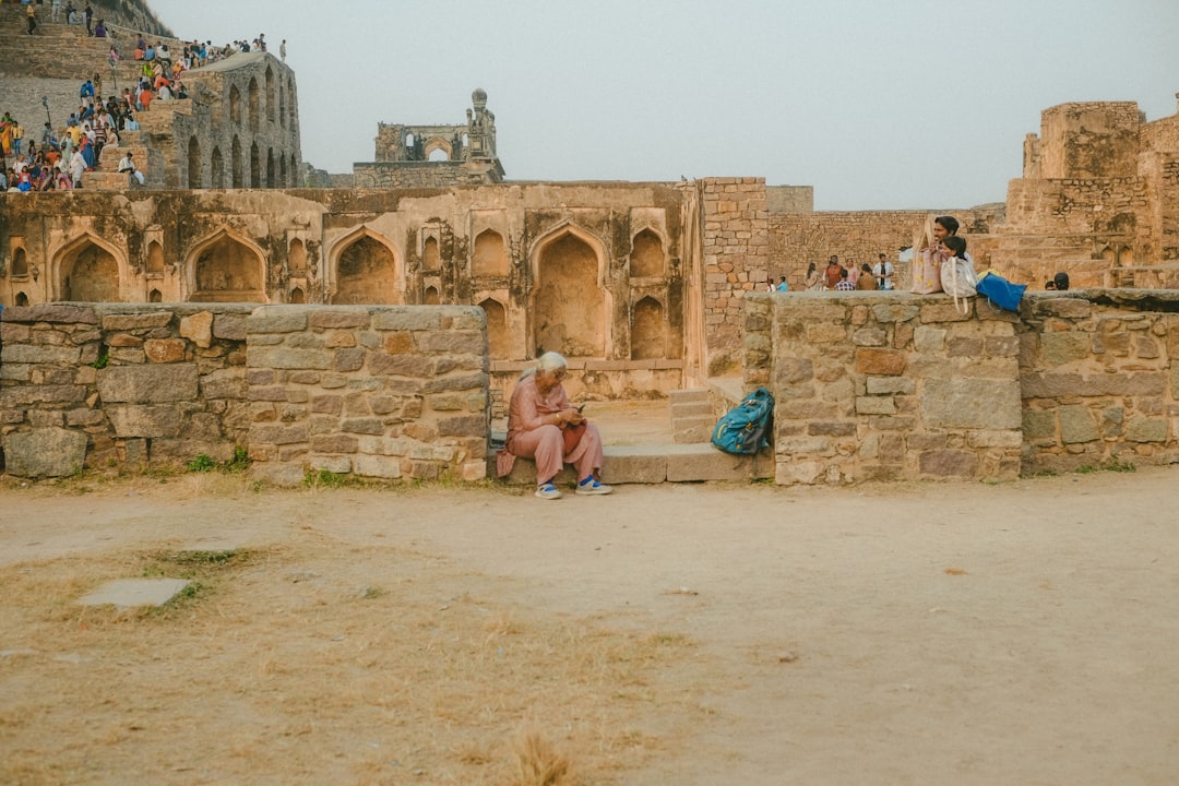 A solo female traveler stands inside the stone gateway of one of the lesser-known Deccan forts in Karnataka