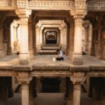 A woman descends the intricate stone steps of one of India's ancient stepwells in Rajasthan in golden morning light