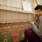 A skilled artisan woman works on a handloom in a regional craft export workshop in India