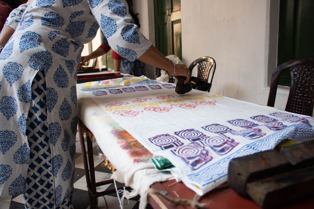 A woman carefully pressing an Indian carved wooden stamp onto cotton fabric during a block printing session at home
