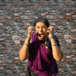 A female vocalist performing Carnatic music on stage at a South Indian concert hall